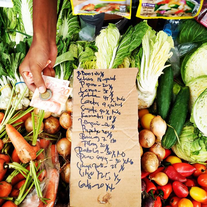 A local market vendor displays a list that shows the prevailing retail price of freshly harvested vegetables. (Photo from BusinessMirror)